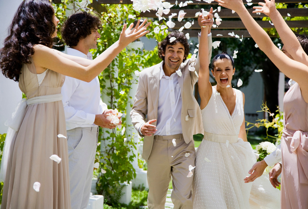 Wedding party tossing petals on bride and groom